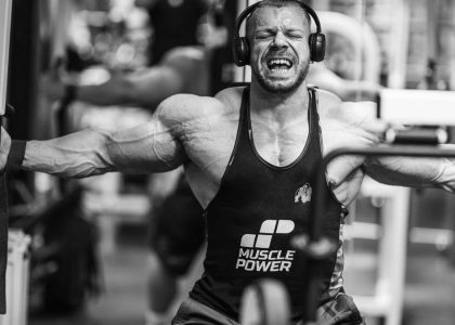 Muscular man intensely working out with gym equipment, showcasing strength and focus.