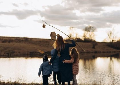 Family enjoying quality time by the lake at sunset with birdhouses.